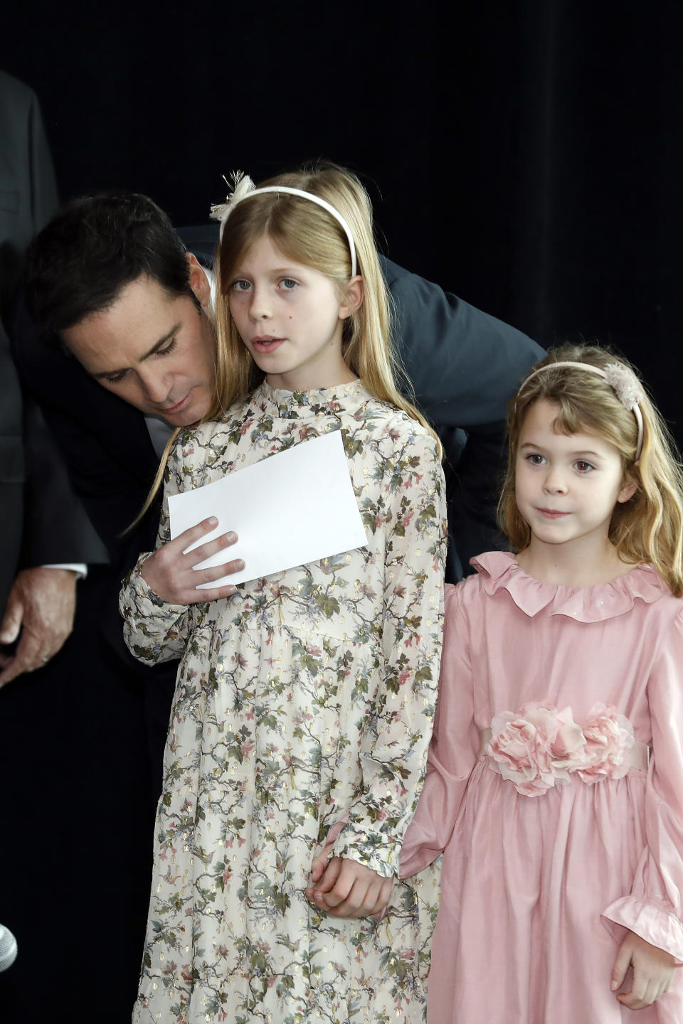 Jimmie Johnson has a word with his oldest daughter, Genevieve, as daughter Lydia waits to take the stage during his NASCAR retirement announcement at Hendrick Motorsports near Charlotte, N.C., Thursday, Nov. 21, 2019. (AP Photo/Bob Leverone)