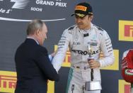 Formula One - Russian Grand Prix - Sochi, Russia - 1/5/16 - Mercedes F1 driver Nico Rosberg of Germany holds his trophy as he shakes hands with Russia's President Vladimir Putin during the Russian Grand Prix. REUTERS/Maxim Shemetov