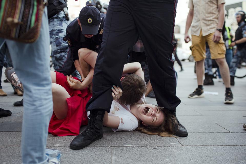 In this photo taken on Saturday, July 27, 2019, Inga Kudracheva screams as her boyfriend Boris Kantorovich lies atop her while police try to detain him during an unsanctioned protest in Moscow. Images of the young couple have been spread on social media. They say the crackdown by police has left them shaken but with their resolve strengthened. (AP Photo/Denis Sinyakov)