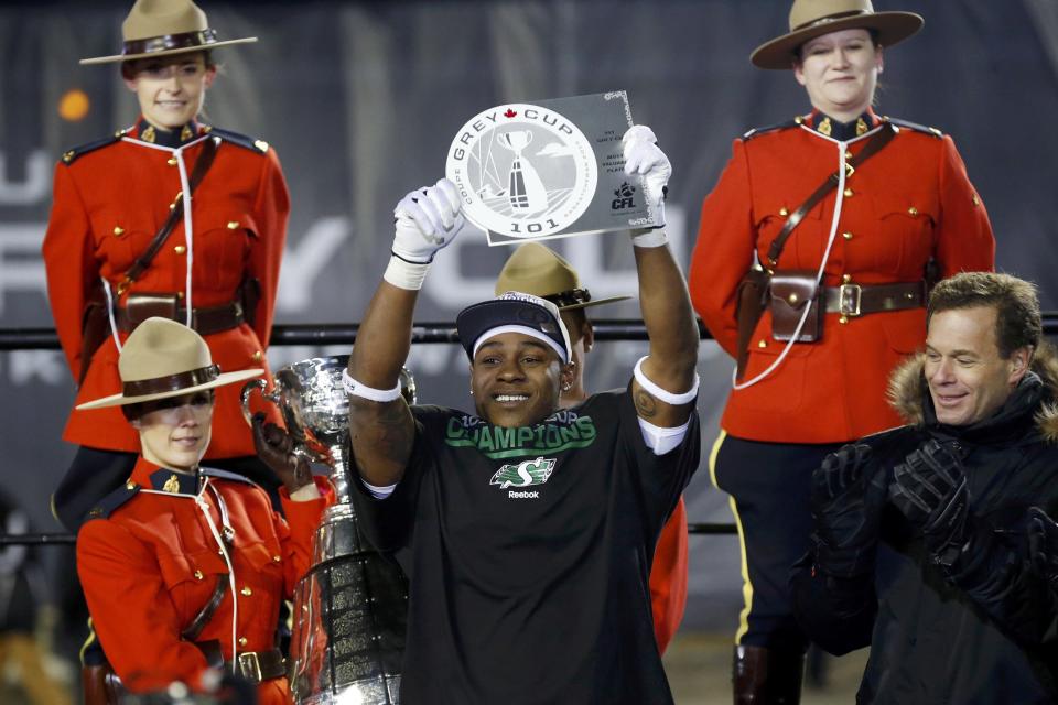 The Saskatchewan Roughriders Kory Sheets (C) holds up the MVP trophy after receiving it from CFL Comissioner Mark Cohon (R) after the Roughriders defeated the Hamilton Tiger-Cats in the CFL's 101st Grey Cup championship football game in Regina, Saskatchewan November 24, 2013. REUTERS/Mark Blinch (CANADA - Tags: SPORT FOOTBALL)