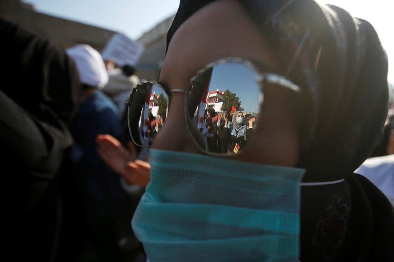 University students are seen in a reflection of glasses during ongoing anti-government protests in Basra