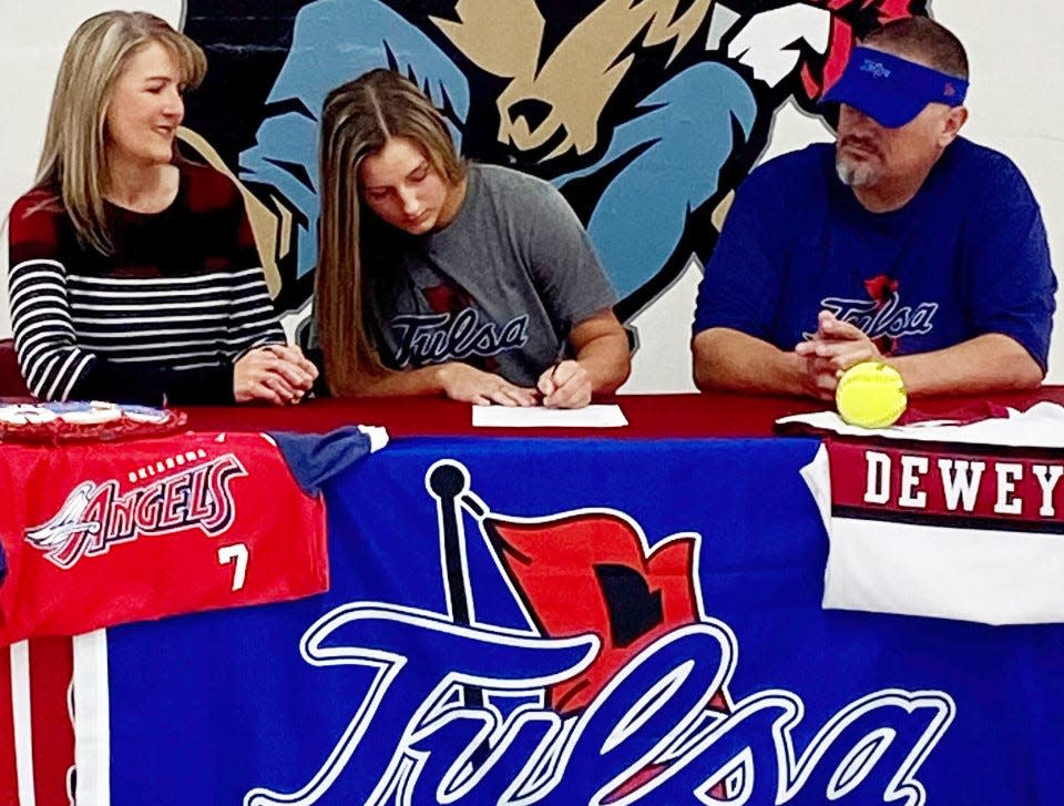 Parents Stephanie, left, and Ryan, right, look on while Dewey High's Gabby Higbee inks her letter of intent to play softball for the University of Tulsa.