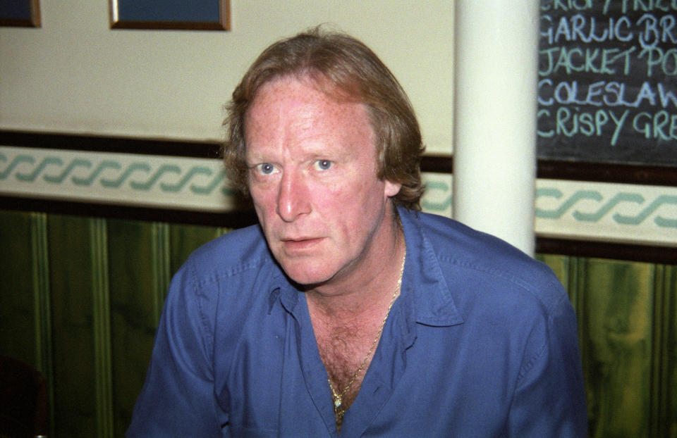 Dennis Waterman sitting in pub restaurant wearing blue shirt