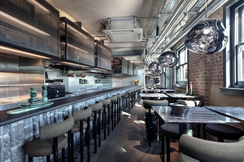 Another space is more monochrome, with gray marble tables, a striking metal bar, and corrugated metal hoods.