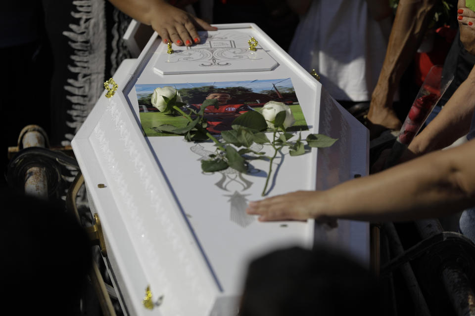 Friends and relatives grieve during the burial of the young soccer player Arthur Vinicius, one of the victims of a fire at a Brazilian soccer academy, in Volta Redonda, Brazil, Saturday, Feb. 9, 2019. A fire early Friday swept through the sleeping quarters of an academy for Brazil's popular professional soccer club Flamengo, killing several and injuring others, most likely teenage players, authorities said. (AP Photo/Leo Correa)