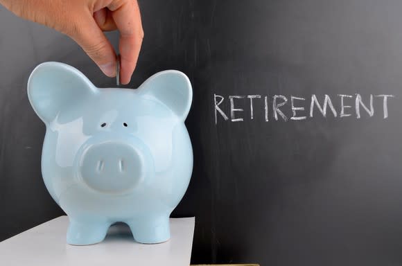 Coin being inserted into piggy bank in front of a chalk board reading "retirement"