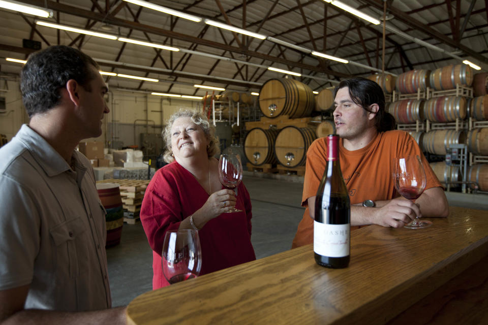 In this photo taken Thursday July 12, 2012, people enjoy the wine tasting room at Dashe Cellars in Oakland, Calif. Growing up in the shadow of an icon is never a shoe-in, whether you’re a wannabe princess related to that attention-grabbing vamp Cinderella or a city living next door to fabled San Francisco. The winery is a producer of some standout zinfandels. (AP Photo/Eric Risberg)