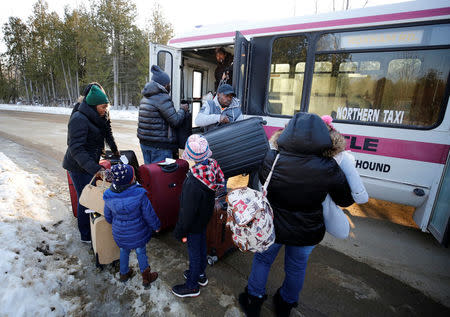 People gather luggage from a shuttle bus as they arrive to cross the US-Canada border into Canada in Champlain, New York, U.S., February 14, 2018. REUTERS/Chris Wattie