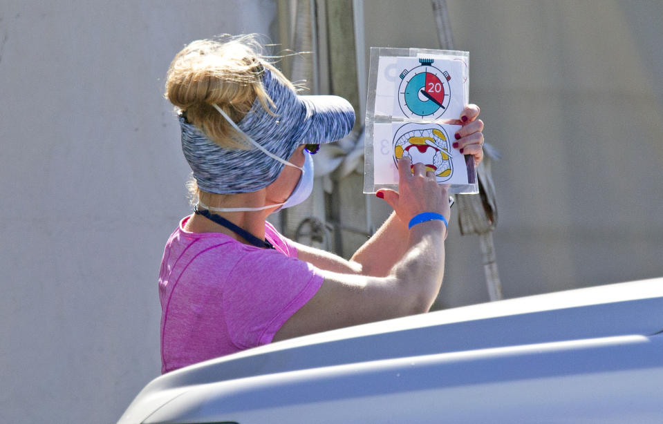 A health care worker direct a person to use a swab for a self administered test at the Miami-Dade County Youth Fairgrounds at Tamiami Park, on Sunday, Nov. 29, 2020 in Miami. (David Santiago/Miami Herald via AP)