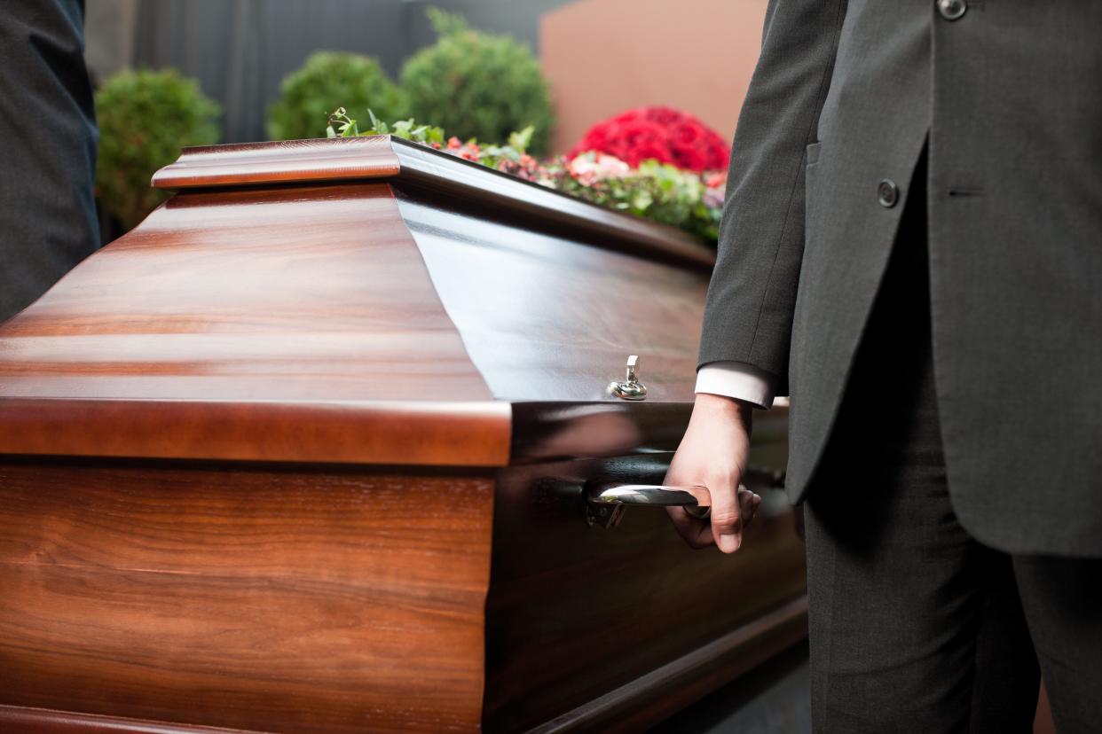 A man appears next to a coffin