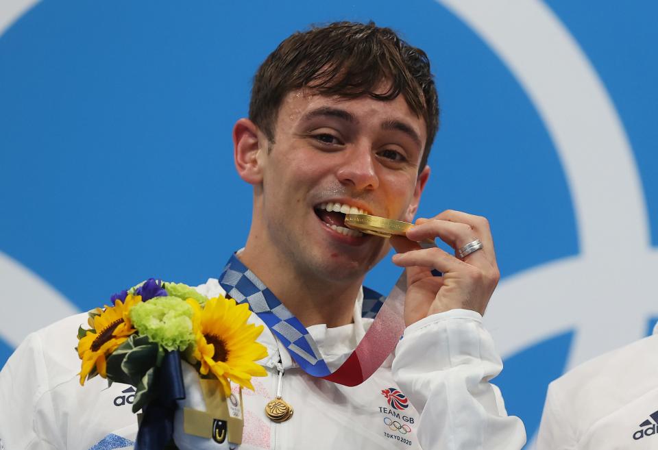British diver Tom Daley biting his Tokyo Olympic gold medal