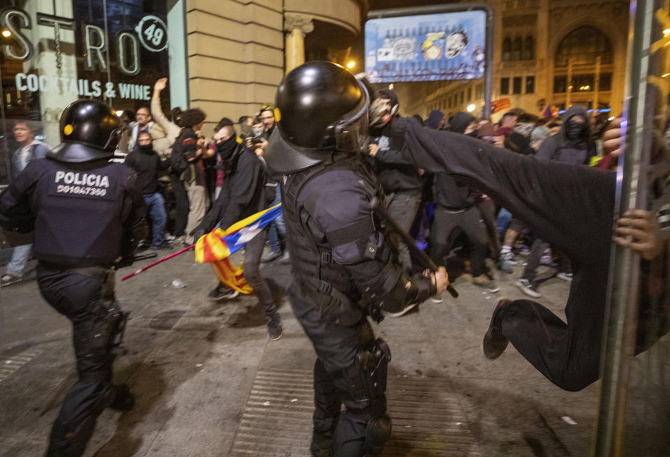 A Catalan pro-independence protester kicks a Catalan Police officer during clashes following a demonstration in Barcelona, Spain, Saturday, Oct. 26, 2019. Protests turned violent last week after Spain's Supreme Court convicted 12 separatist leaders of illegally promoting the wealthy Catalonia region's independence and sentenced nine of them to prison. (AP Photo/Emilio Morenatti)