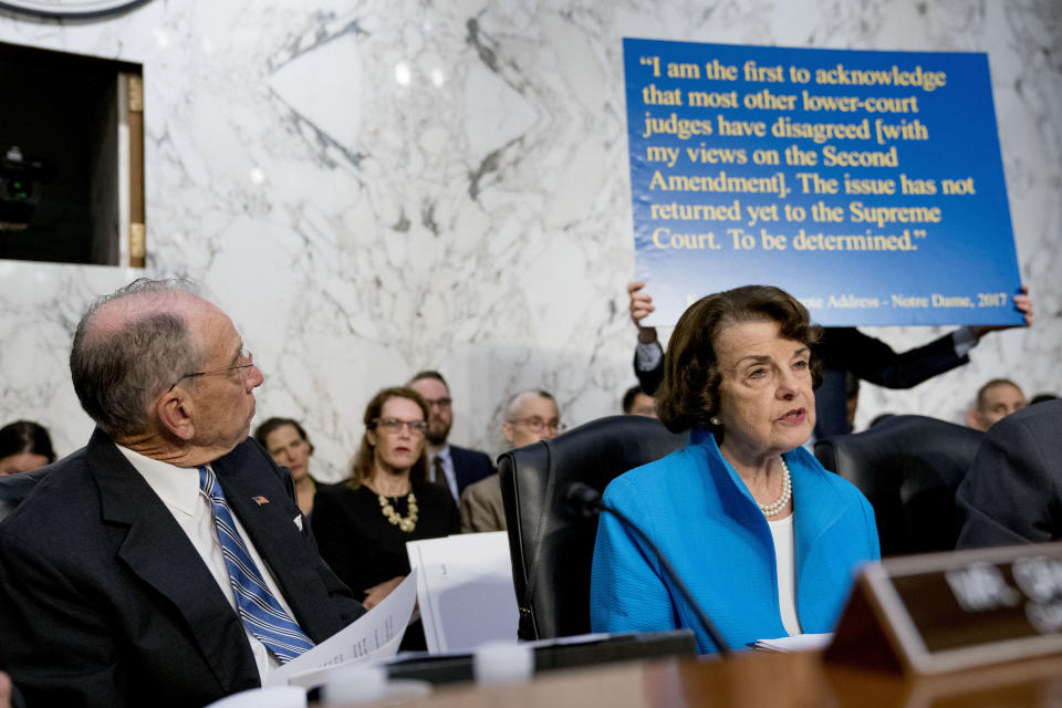 A poster depicting a 2017 quote on the Second Amendment by President Trump’s Supreme Court nominee, Brett Kavanaugh, is held up behind Sen. Dianne Feinstein, D-Calif., as she questions Kavanaugh on Capitol Hill in Washington on Thursday, the second day of his confirmation hearings. Senate Judiciary Committee Chairman Chuck Grassley, R-Iowa, looks on. (Photo: Andrew Harnik/AP)