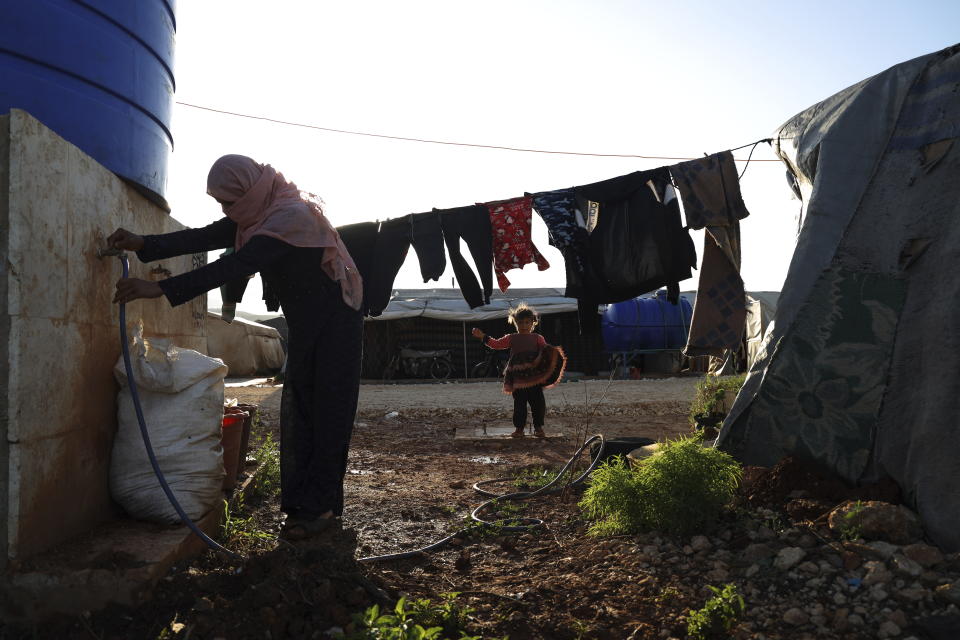 A displaced Syrian woman Rudaina al-Salim runs errands for her family at a tent encampment in the village of Harbnoush, in Idlib province, Syria, Monday, May 13, 2024. Syria's devastating civil war, now in its 14th year, remains largely frozen and so are efforts to find a viable political solution to end it, while millions of Syrians have been pulled into poverty, and struggle with accessing food and health care as the economy deteriorates across the country's front lines. Aid organizations are making their annual pitches to donors ahead of a fundraising conference in Brussels for Syria on Monday, May 27. (AP Photo/Omar Albam)