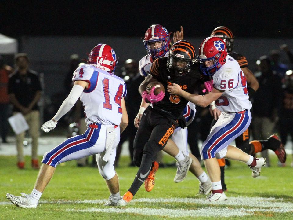 Licking Valley's Caden Rhodes (56) grabs an East ball carrier while Carter Hartman (14) moves into position to assist on Friday.