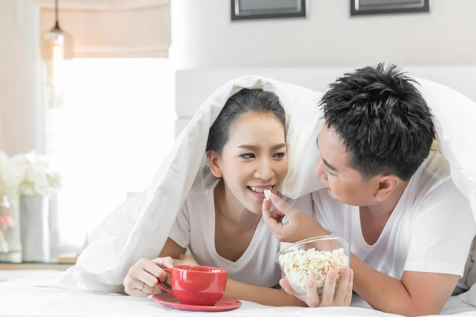 A couple having breakfast on bed together to depict a strong relationship that could be lacking in intimacy.