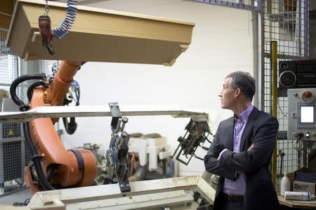 Coffin maker Michael Jagdt (CEO of lignotech Massivholz GmbH) watches a robot arm moving a coffin in Berlin, December 1, 2014. REUTERS/Axel Schmidt