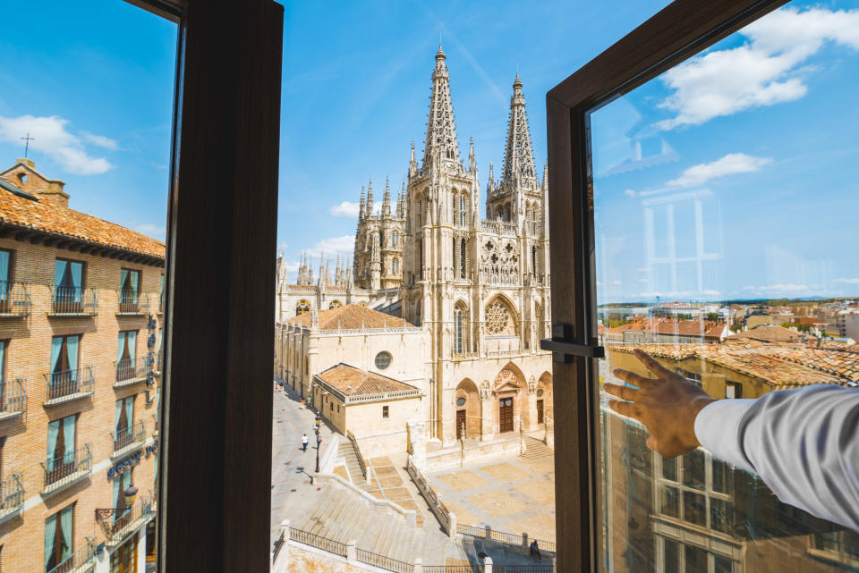 Well-dressed man with white shirt opening the window overlooking at the Burgos cathedral, Castilla y Leon, Spain