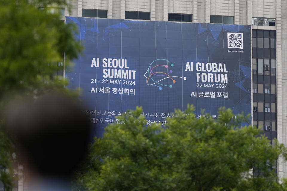 A man on a bicycle passes by a huge banner for the upcoming AI Seoul Summit and AI Global Forum in Seoul, South Korea, Monday, May 20, 2024. South Korea is set to host a mini-summit this week on risks and regulation of artificial intelligence, following up on an inaugural AI safety meeting in Britain last year that drew a diverse crowd of tech luminaries, researchers and officials. (AP Photo/Lee Jin-man)