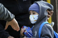 A teacher reaches her hand out to Pedro Garcia, 4, as he arrives for the first day of school at the Mosaic Pre-K Center in Queens, Monday, Sept. 21, 2020 in New York. The city public schools delayed reopening for two weeks. (AP Photo/Mark Lennihan)