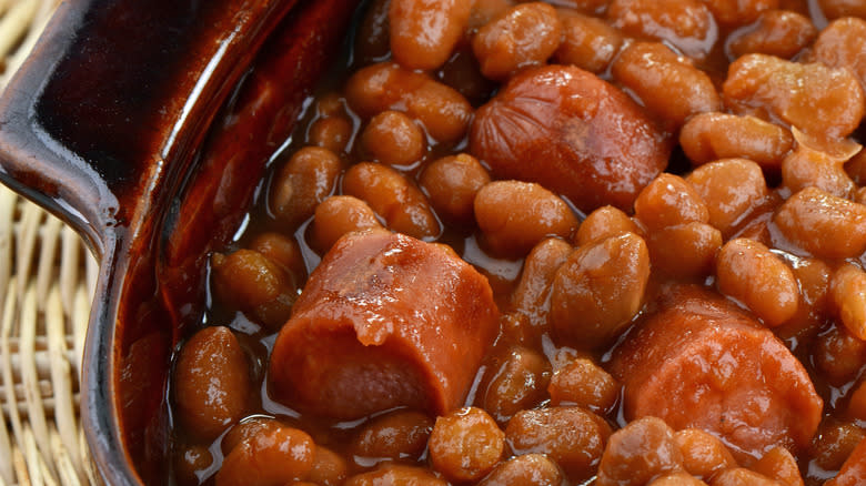 Closeup of hot dogs and baked beans in a ceramic crock
