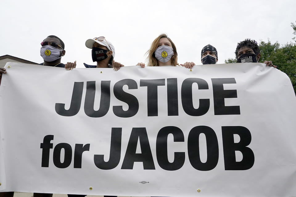 Participants in a community gathering at the site of Jacob Blake's shooting hold a sign in support of justice during speeches Tuesday, Sept. 1, 2020, in Kenosha, Wis.