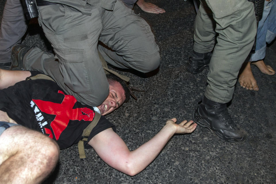 File - In this Wednesday, July 22, 2020 file photo, an Israeli police officer puts his knee on a demonstrator during a protest against Israel's Prime Minister Benjamin Netanyahu outside his residence in Jerusalem. (AP Photo/Ariel Schalit, File)