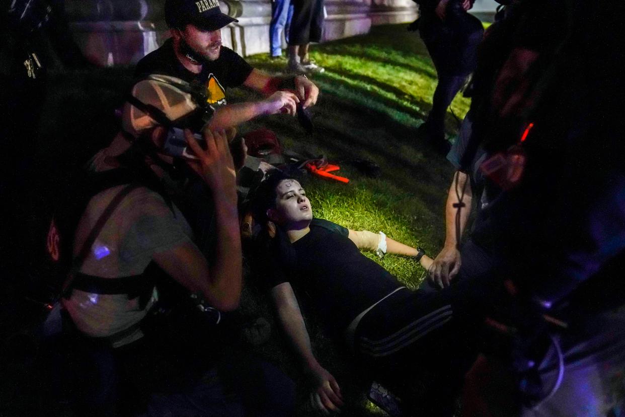 In this Aug. 25, 2020 file photo, Gaige Grosskreutz, top, tends to an injured protester during clashes with police outside the Kenosha County Courthouse in Kenosha, Wis.