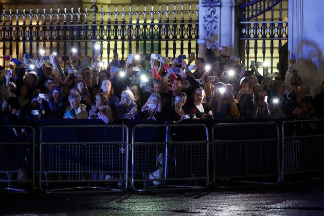 Members of the public are lit by their mobile phones as they await the arrival of the hearse. (Photo: Chip Somodevilla/Getty Images)