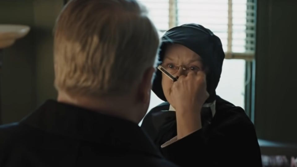 Meryl Streep, as a Catholic nun, holds a crucifix in the face of a priest