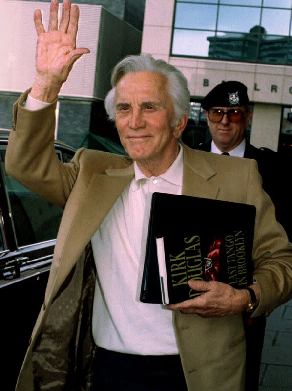 FILE PHOTO: Veteran actor Kirk Douglas waves as he arrives at the Glasgow Hilton, in Glasgow, Britain