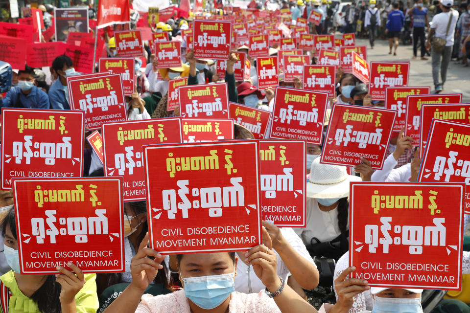 Anti-coup protesters hold up signs that read "Civil Disobedience Movement Myanmar" during a rally in Mandalay, Myanmar Friday, Feb. 19, 2021. A young woman who was shot in the head by police during a protest last week against the military's takeover of power in Myanmar died Friday morning, her brother said. (AP Photo)