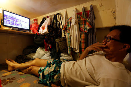 Unemployed Hong Kong resident Simon Wong, 61, watches TV inside his 4-by-6-feet partitioned unit, or "coffin unit", with a monthly rent of HK$1,750 ($226) in Hong Kong, China October 31, 2016. REUTERS/Bobby Yip