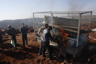 An Israeli Jewish settler tries to prevent a Palestinian from torching a trailer during a protest against the expansion of Jewish settlements near the West Bank town of Salfit, Monday, Nov. 30, 2020. In years to come, Israelis will be able to commute into Jerusalem and Tel Aviv from settlements deep inside the West Bank via highways, tunnels and overpasses that cut a wide berth around Palestinian towns. Rights groups say the new roads that are being built will set the stage for explosive settlement growth, even if President-elect Joe Biden's administration somehow convinces Israel to curb its housing construction. (AP Photo/Majdi Mohammed)