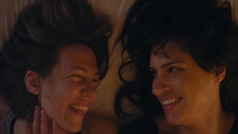 photo of two dark haired women facing each other while laying down and smiling