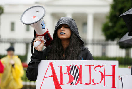 Madvhi Venkatraman closes her eyes as she listens to the cries of illegal immigrant children held in a U.S. detention facility after being separated from their parents that she is playing through her megaphone during a protest against the separation of immigrant families outside the White House in Washington, U.S., June 22, 2018. REUTERS/Jim Bourg