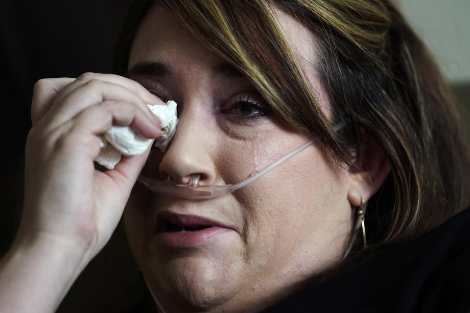 Lauren Debroeck, who is on oxygen as she recovers from COVID-19, cries as she talks about her family, at the bedside of her husband, Michael, who also contracted COVID-19 and is being kept alive with the help of an oxygenation machine, at the Willis-Knighton Medical Center in Shreveport, La., Wednesday, Aug. 18, 2021. (AP Photo/Gerald Herbert)