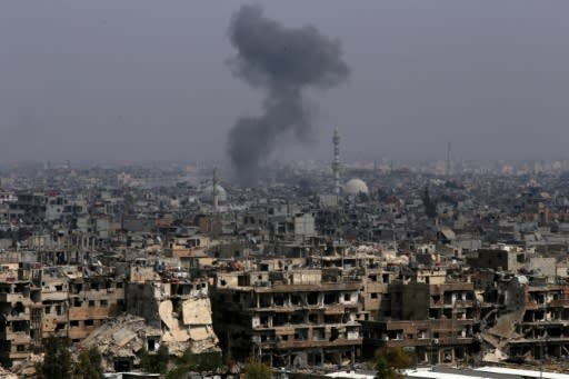 Smoke rises from buildings in Yarmuk, a Palestinian refugee camp on the edge of Damascus, during regime shelling targeting Islamic State group positions in the southern district of the capital on April 28, 2018