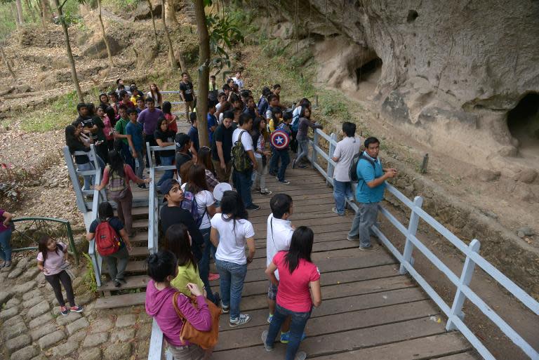 Visiting students look at the carvings on a rock wall in Binangonan, east of Manila, on February 16, 2014