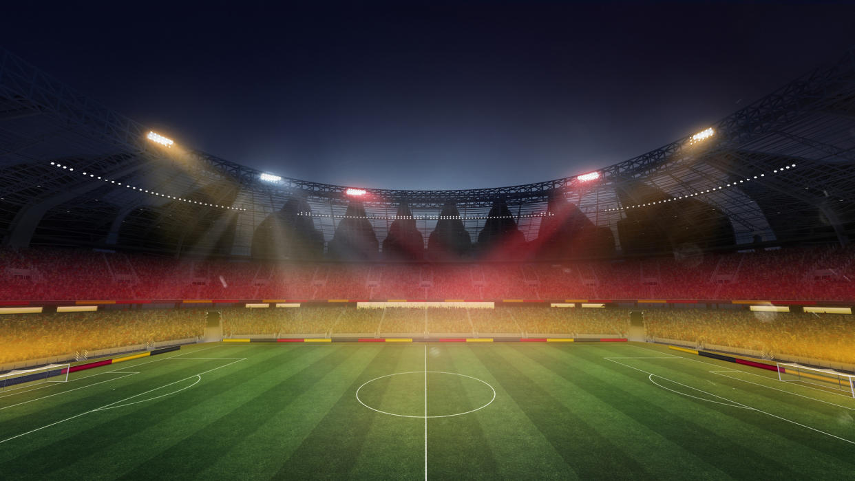  An empty football field lit in the colours of the German flag. 