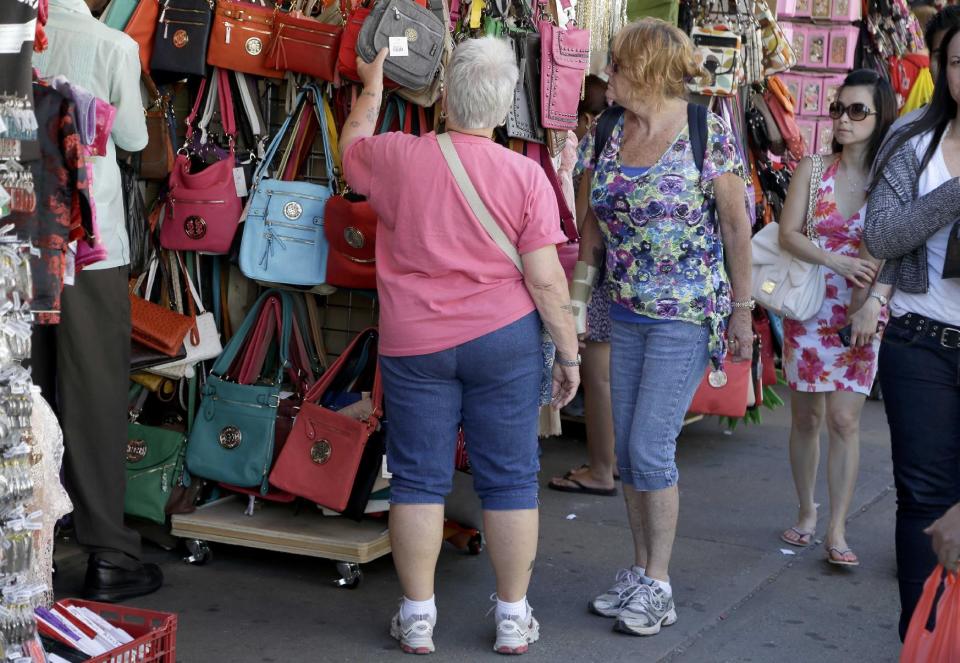 Women looks over a display of purses on Canal Street in New York, Tuesday, June 4, 2013. Bargain hunters from around the world flock to Manhattan's Chinatown for legally sold bags, jewelry and other accessories bursting onto sidewalks from storefronts along Canal Street. (AP Photo/Seth Wenig)