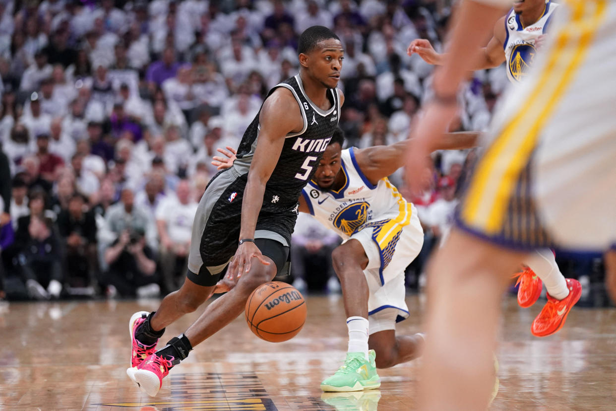 Sacramento Kings guard De'Aaron Fox (5) dribbles past Golden State Warriors forward Andrew Wiggins (22) in the first quarter during game one of the 2023 NBA playoffs at the Golden 1 Center.