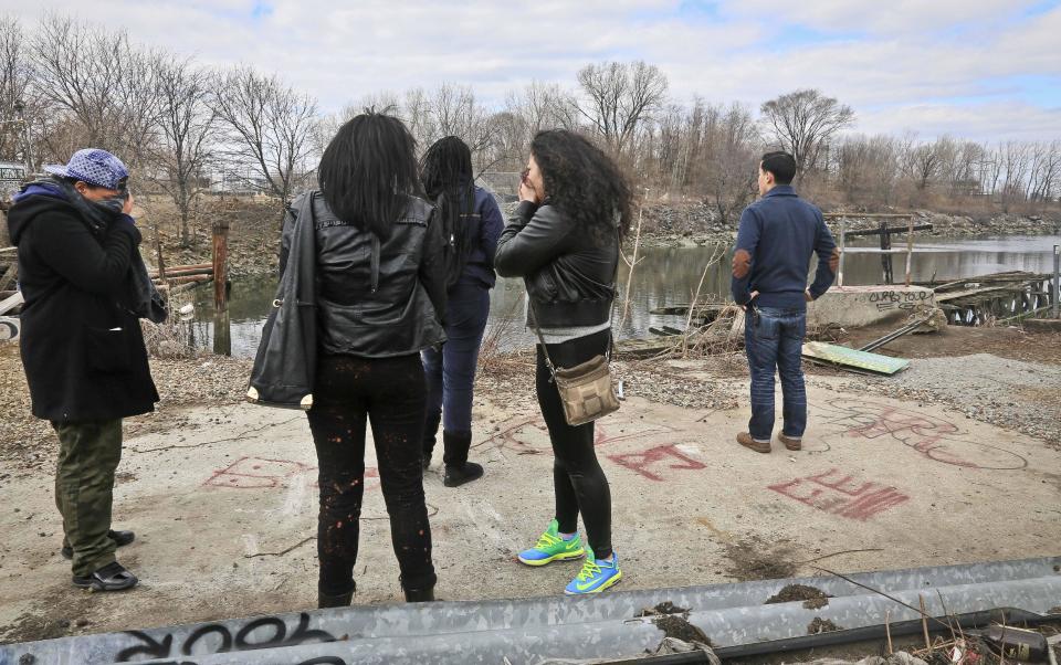 Friends mourn as they stand near Steinway Creek at an accident site on Saturday April 5, 2014 in New York. A driver of a car drove off a dead-end street in a desolate industrial area, flipped over a wooden curb into the East River inlet killing four passengers. The driver escaped serious injury and told officers at the scene in the Astoria section of Queens that the four were trapped in the submerged car. Fire department divers pulled the four victims from the car. Police identified them as 21-year-old Darius Fletcher, 19-year-old Jada Monique Butts, 19-year-old Crystal Gravely and 20-year-old Jaleel Furtado. They were pronounced dead at hospitals. (AP Photo/Bebeto Matthews)