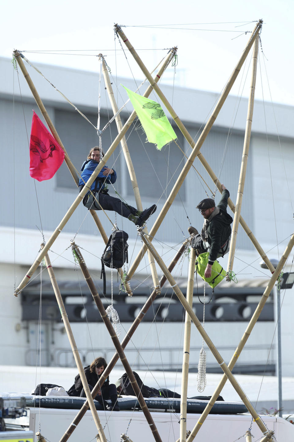 Two protesters attached to bamboo and two sitting on the roof of a van block the road, outside Broxbourne newsprinters, in Broxbourne, Hertfordshire, England, Saturday, Sept. 5, 2020. Environmental activists have blockaded two British printing plants, disrupting the distribution of several national newspapers. The group Extinction Rebellion said it targeted printworks at Broxbourne, north of London, and Knowsley in northwest England that are owned by Rupert Murdoch’s News Corp. Dozens of protesters locked themselves to vehicles and bamboo scaffolding to block the road outside the plants. The facilities print Murdoch-owned papers The Sun and The Times, as well as the Daily Telegraph, the Daily Mail and the Financial Times. (Yui Mok/PA via AP)