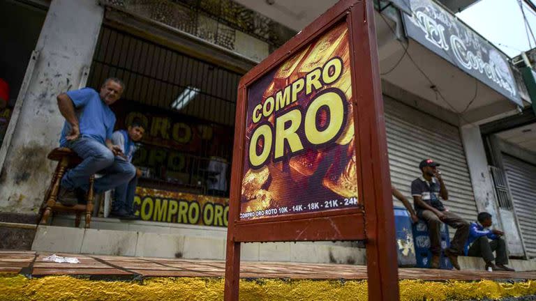 Hombres sentados a las afueras de un negocio de compra de oro en El Callao, estado Bolívar, en el sureste de Venezuela