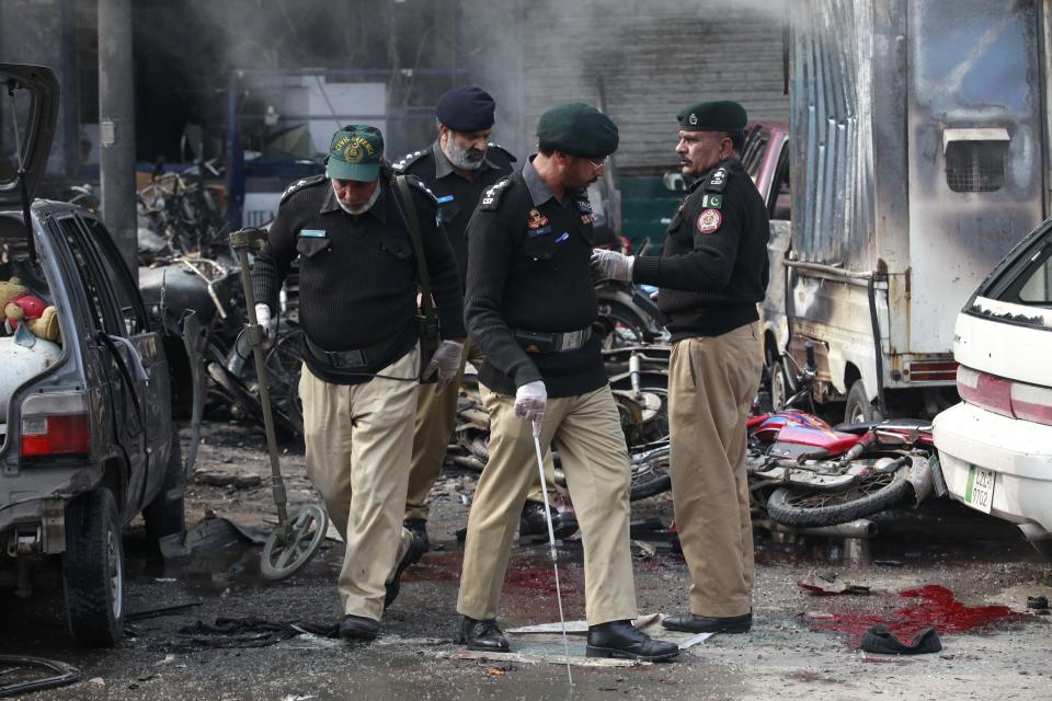 Policemen inspect the site of an explosion outside the police headquarters, in Lahore