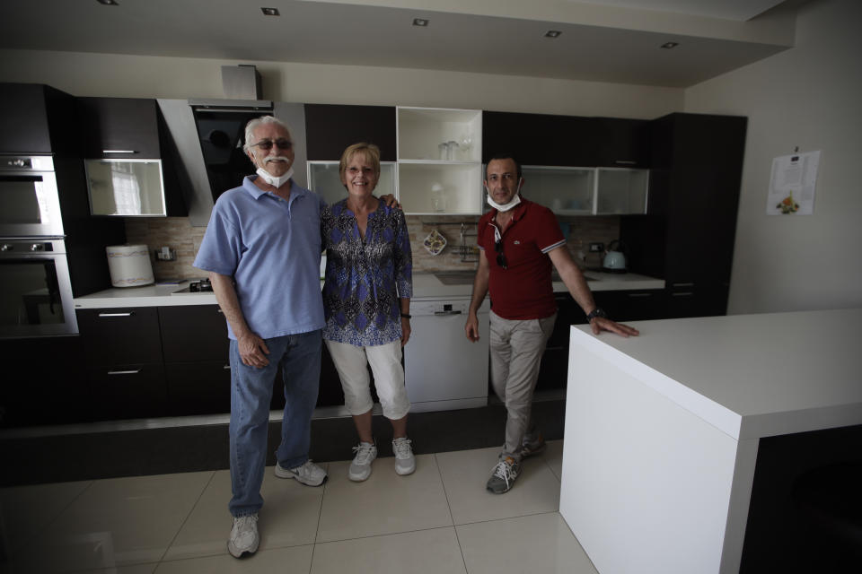 Marvin and Colleen Hewson, from the United States, pose for a photograph with Fabio Sposato, right, the owner of the apartment where they stayed in Pompeii, near Naples, southern Italy, Tuesday, May 26, 2020. An American couple waited a lifetime plus 2 ½ months to visit the ancient ruins of Pompeii together. For Colleen and Marvin Hewson, the visit to the ruins of an ancient city destroyed in A.D. 79 by a volcanic eruption was meant to be the highlight a trip to celebrate his 75th birthday and their 30th anniversary. They were among the only tourists present when the archaeological site reopened to the public on Tuesday after the national lockdown to prevent the spread of COVID-19. (AP Photo/Alessandra Tarantino)