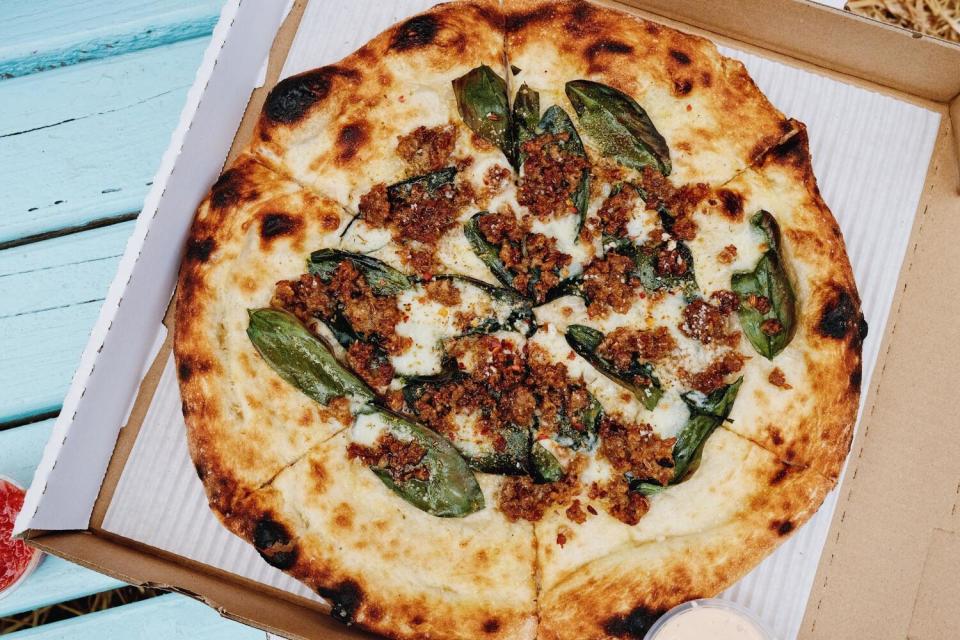A fava leaf and sausage pizza in a box