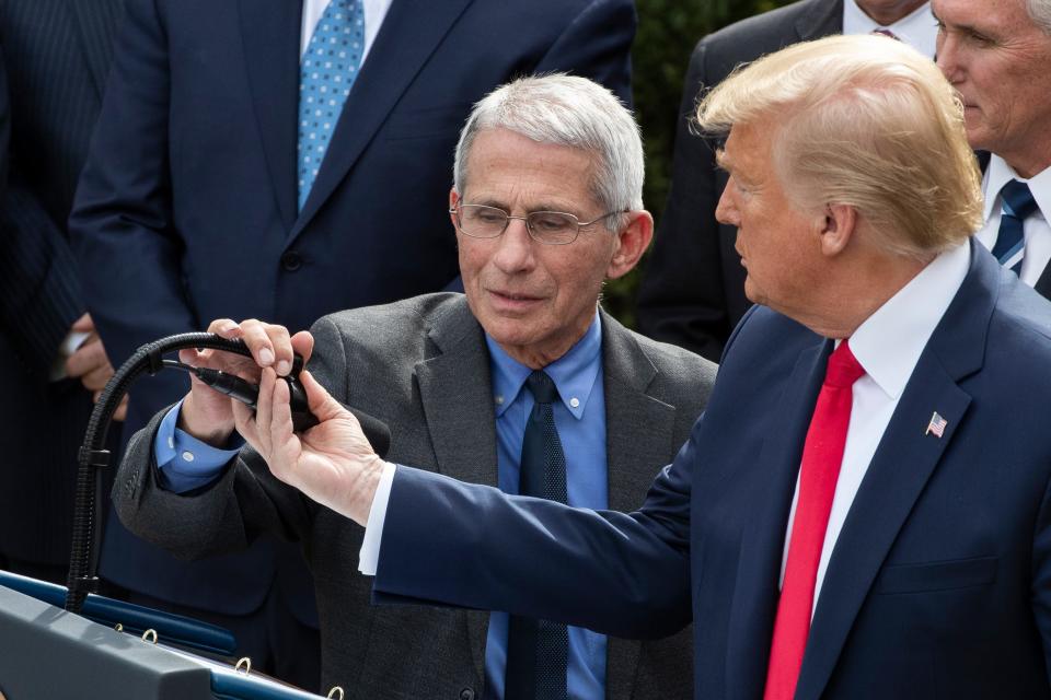 President Donald Trump assists Dr. Anthony Fauci, director of the National Institute of Allergy and Infectious Diseases with the microphone as he speaks during a news conference about the coronavirus in the Rose Garden at the White House, Friday, March 13, 2020, in Washington. (AP Photo/Alex Brandon) ORG XMIT: DCAB129