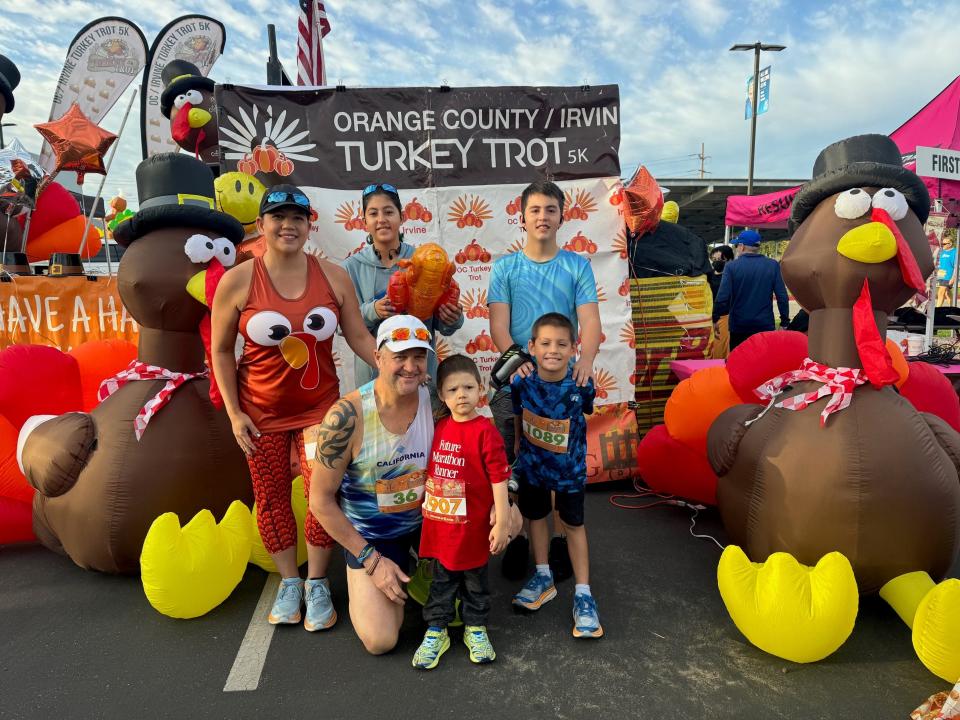A family stands in front of a sign advertising the turkey trot they ran.
